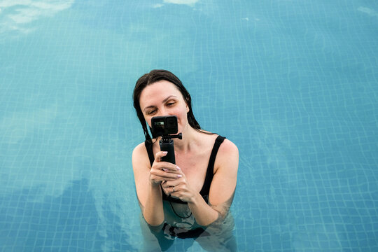 Woman in a Pool Holding Action Camera