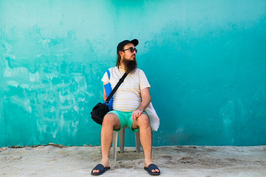 Relaxed Man Sitting by a Teal Wall in Maafushi