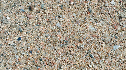 Stones and sand in the summer day. Yellow sand on the beach near a sea.