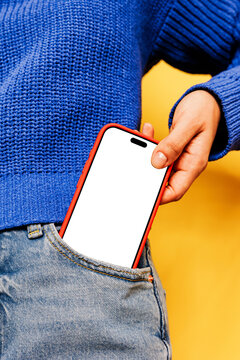 Woman putting smartphone with blank screen in jeans pocket