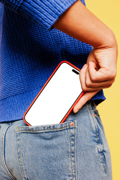 Woman putting smartphone with blank screen into back pocket of jeans