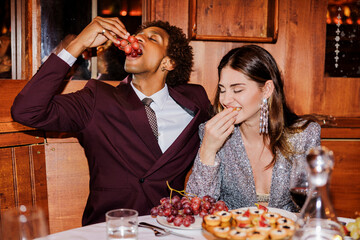 Elegant couple enjoying grapes and appetizers at restaurant table ugc