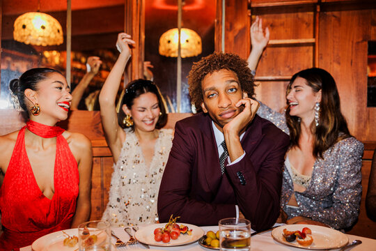Elegant man sitting at table while friends dancing at New Year's ugc