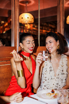 Two elegant women enjoying appetizers and drinks at restaurant ugc