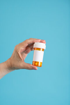 Hand holding prescription pill bottle. Mock up, blank label. 