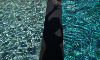 A shadowy figure rests by the shimmering poolside