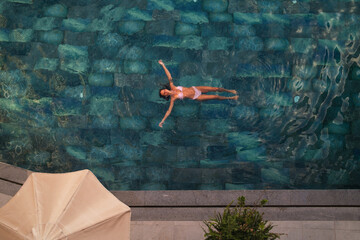 A woman relaxes while floating in a serene swimming pool 