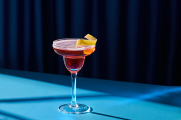 Elegant Cocktail with Lemon Twist on Blue Background