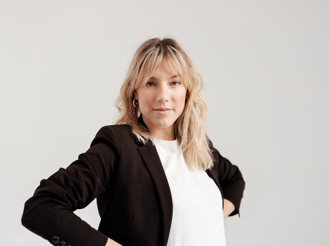 Confident Professional Woman in Black Blazer Posing Against Whit