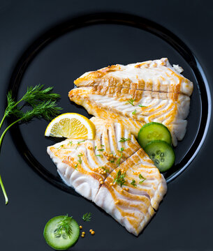 Grilled Pollack fish fillets garnished with fresh herbs and citrus