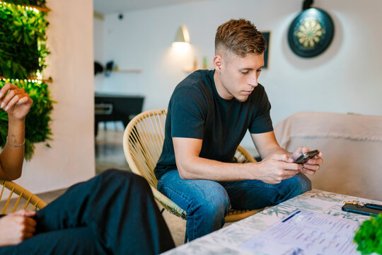 Young man using smartphone in modern office with colleague