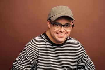 Smiling man with Down syndrome wearing cap and striped sweater