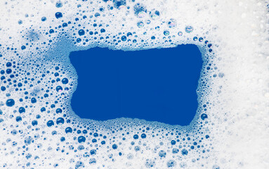 Foam background. Liquid soap bubbles, Frame made of Froth bubbles, on blue backdrop. Soap foam...