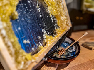 Honeycomb with wax and honey on a wooden table of the hotel restaurant in a beekeeper's apiary. Close up.