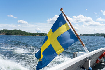 Swedish flag waving from boat in Stockholm archipelago on sunny day