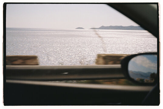 Scenic view of a tranquil coastline captured from a moving car 