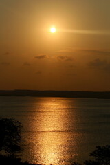Sunset at the lagoon, with sunlight reflecting off the water, with the forest in the background, on the horizon