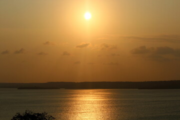 Sunset at the lagoon, with sunlight reflecting off the water, with the forest in the background, on the horizon