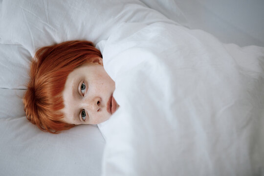 Natural woman resting under white bedding