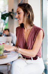Positive woman typing on laptop in cafe
