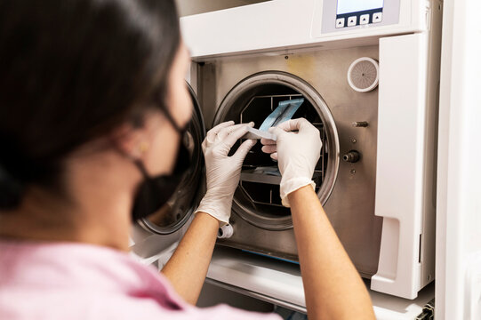 Dentist setting dental tools in autoclave for sterilization