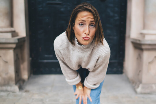 Woman with grimace stooping standing at building