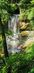 A waterfall hidden by the trees and leaves in the summer.