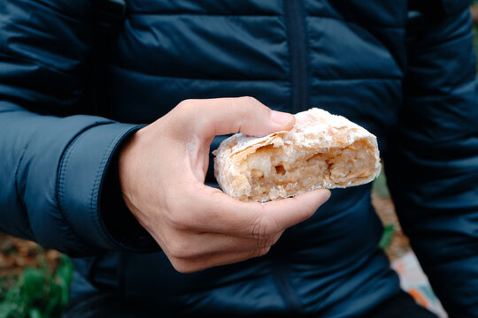 man about to eat a piece of apple strudel on the street