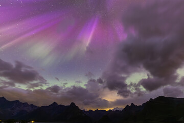 The stunning Northern Lights over Lofoten Islands, Norway, with vivid colors lighting up the night sky above mountains.