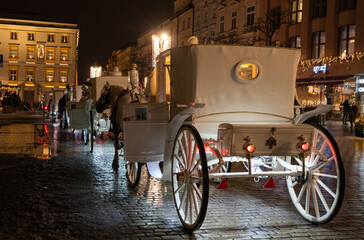 elegancka  biała dorożka konna na ulicach Krakowa wieczorową porą © siwyk