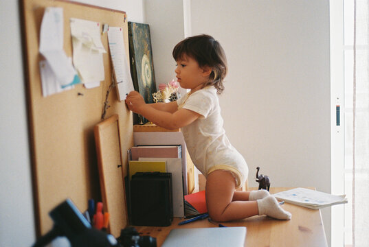 Toddler exploring papers on a home corkboard