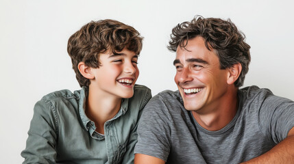 Obraz premium Joyful studio portrait of father and teenage son bonding and laughing together