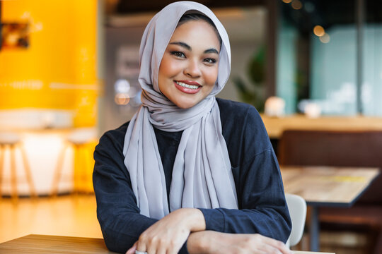 Confident young woman in hijab at cafe
