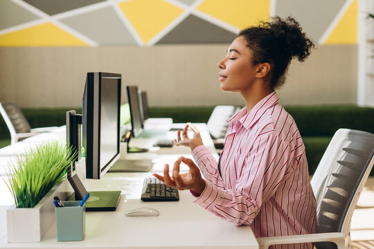 Office worker meditating at her desk for stress relief