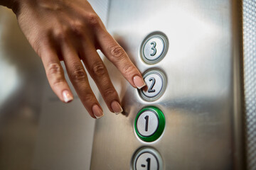 Pressing the elevator button in contemporary high rise buildings signifies modern urban convenience