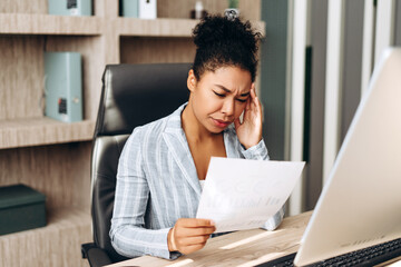 Stressed manager reading bad news in financial report at office desk