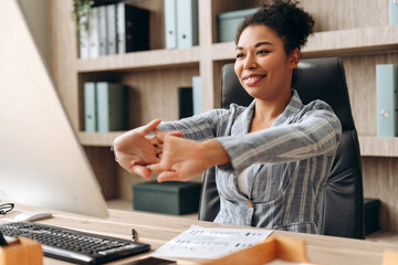 Smiling businesswoman stretching arms at office desk
