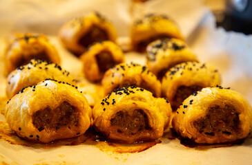 Tradtional puff pastry pork sausage rolls topped with nigella seeds. Organic pork snack. Food photography.