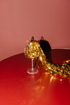 Elegant Wine Glass with Festive Gold Tinsel on Red Table