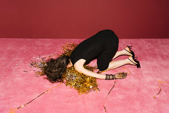 Woman Lying on Pink Carpet With Party Confetti and High Heels