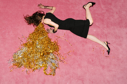 Woman in Black Dress Lying on Pink Floor with Confetti