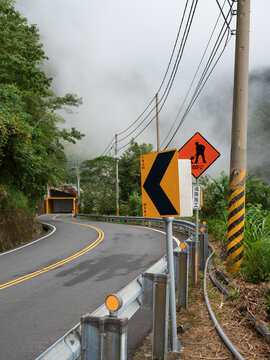 Winding mountain road with signs and tunnel, Taiwan.