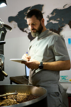 Coffee roaster monitoring beans while taking notes 