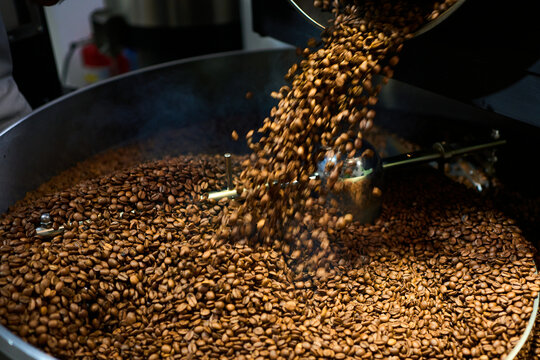 Freshly roasted coffee beans being poured from a roaster at a caf&eacute;