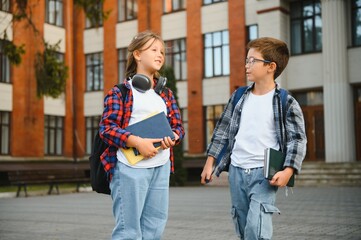 Happy children near the school. Friends boy and girl together in the school yard
