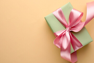 Beautiful gift box with pink bow on beige background, top view. Space for text