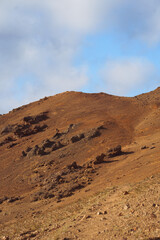 Geothermal terrain with steaming vents, golden-orange soil, and rocky formations near Námafjall, Iceland.