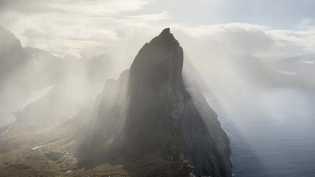 Fog is surrounding a Segla peak over the ocean in Senja, Norway