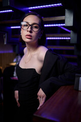 An Elegant Model Dressed in a Chic Black Outfit Poses at a Modern Bar Setting for Photography