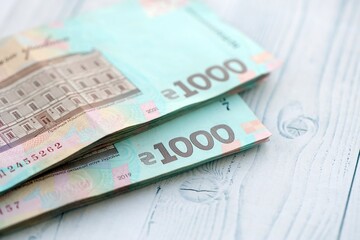 Big amount of ukrainian new one hundred hryvnia money bills with modern design on white wooden table. Financial concept, business